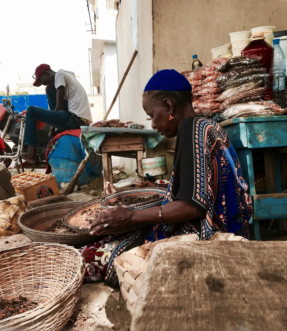 Une commerçante trie des graines dans des paniers devant son étal.